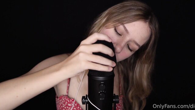 Blonde ASMR girl in spaghetti top grips black mic close-up, Diddly Mic Pumping