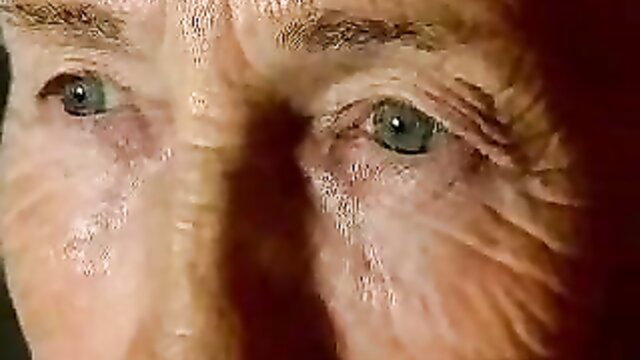 Closeup of sexy 80-year-old grandma's green eyes and wrinkled face