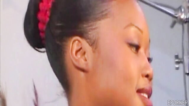 Closeup of smiling black beauty with red hair bun in steamy sex scene