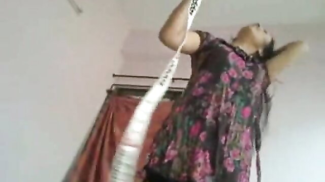 Indian nympho in purple dress holds white object, arms up teasingly