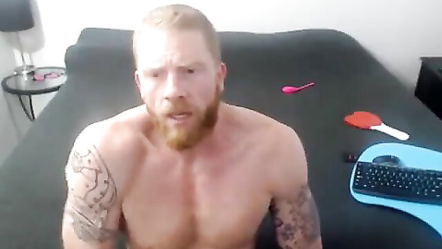 Shirtless muscular ginger bearded man posing nude on bed