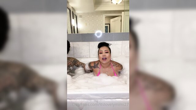 Tattooed Asian Mimi in pink bikini bubble bath with man