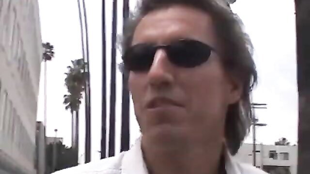 Mature man with sunglasses in white shirt on sunny LA street