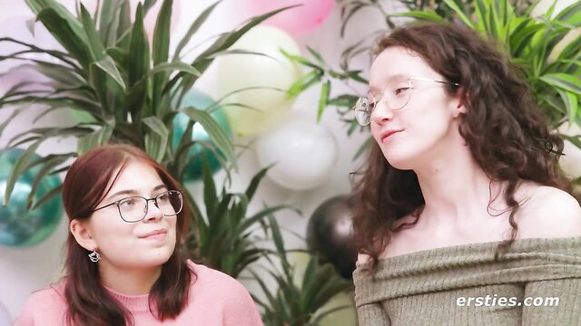 Two amateur chicks in glasses smile at party with balloons