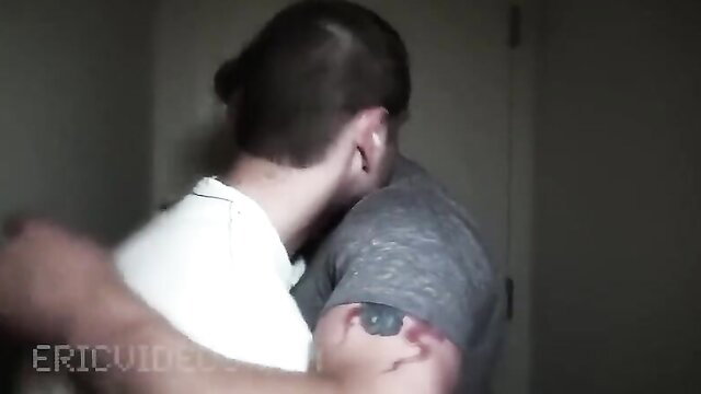 Two hot men in intense gay embrace, one with man bun and arm tattoo