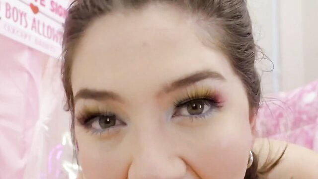 Closeup of seductive girl's sultry eyes and glossy lips in pink bedroom