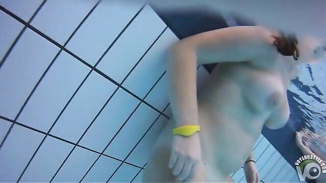 Nude woman swimming underwater in nudist camp pool