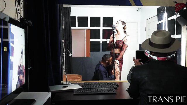 Trans woman in lingerie performs for kneeling black man in studio shoot