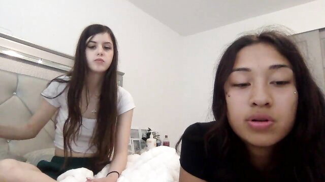 Lizzyhart and friend petite camgirls on bed, teasing in tops and skirts