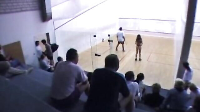 Busty babe stripping in racquetball court with crowd watching