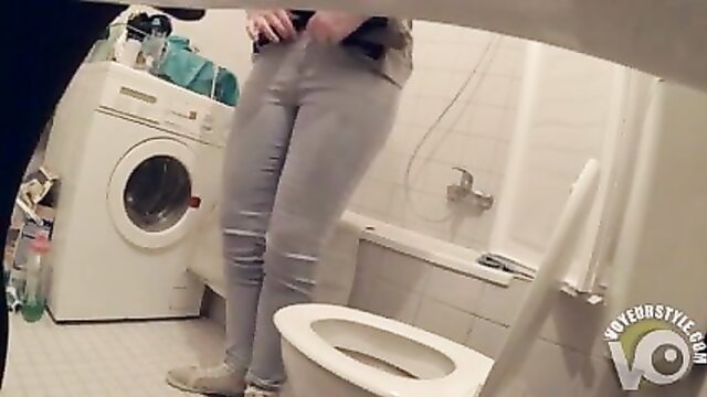 Slim brunette teen pulling down gray jeans to pee in toilet POV