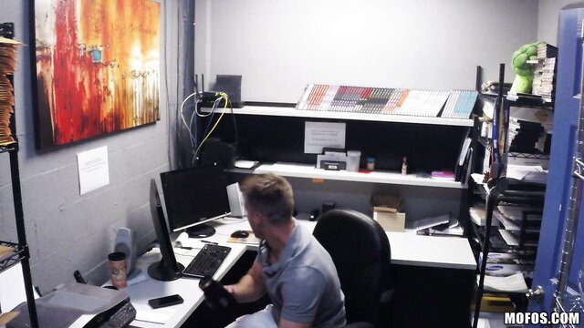 Man working at cluttered office desk caught on spy cam