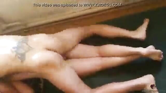 Nude tattooed Asian man lying spread-legged on floor exposing cock