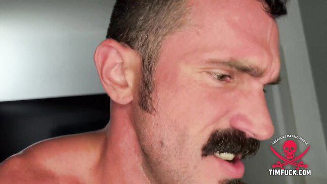 Muscular man with thick mustache snarls intensely in gay porn thumbnail