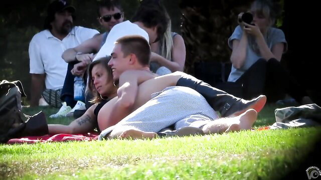 Short-haired brunette makes out with guy on picnic blanket outdoors