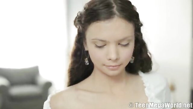 Sensual teen beauty with long wavy hair in white dress bares shoulders