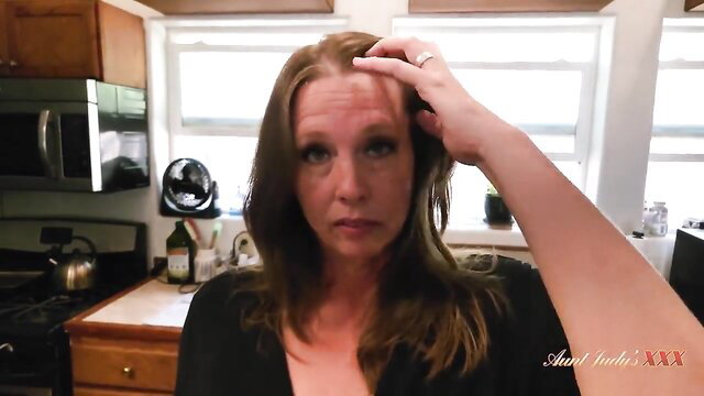 Hot amateur mommy with brown hair touching face in kitchen