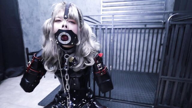 Asian bondage pet in latex harness gag chained in cage