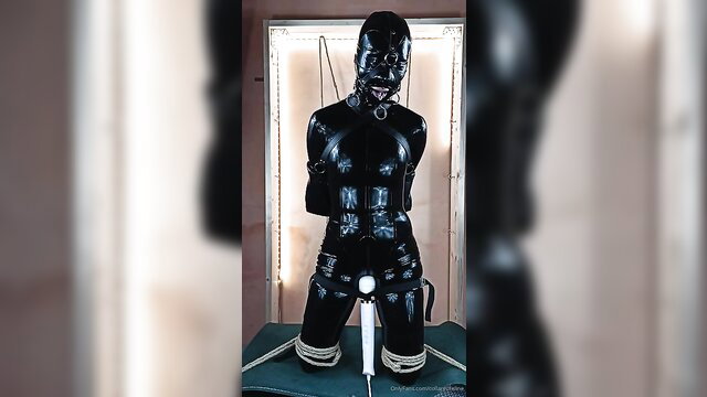Shiny black latex catsuit bondage sub kneeling with hood and gag