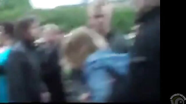 Blurry crowd scene with blonde woman in blue jacket, drunk piss fail vibe