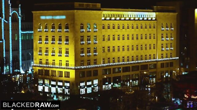 Lit-up city building at night with holiday lights, yellow glow