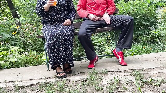 Curvy wife in floral dress sips drink with hubby on bench outdoors