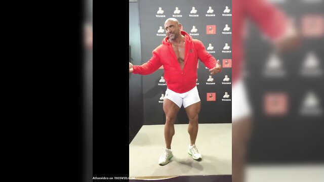 Bald muscular hunk in red hoodie and white briefs strips at event
