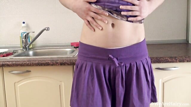 Hairy cutie lifting top flashing abs in purple skirt in kitchen