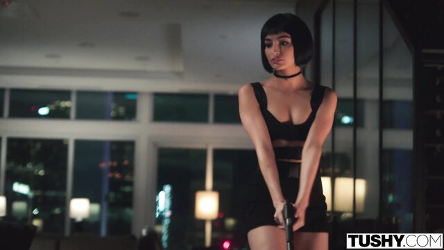 Emily Willis in sexy black cutout dress holds gun seductively