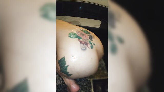 Japanese woman bent over bathtub showing floral tattooed ass in enema play