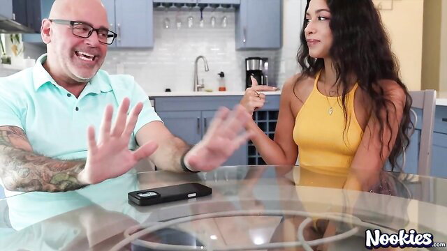 Luxe La Fox chats with bald tattooed man at table in yellow dress