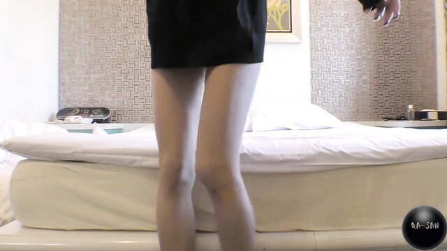 Serika in tight black minidress teases long legs by bed