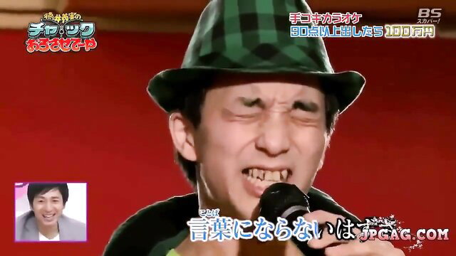 Japanese man in green hat grimacing during handjob karaoke game show