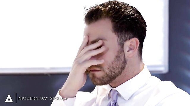 Seth Gamble facepalms in suited office scene from Modern Day Sins