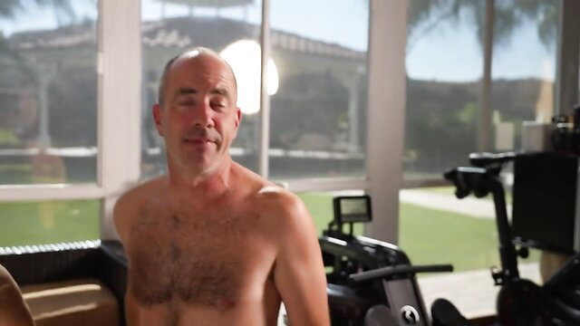 Bald silver fox daddy shirtless in home gym smiling
