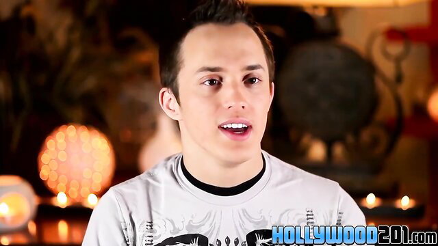 Young twink Kain Lanning talks on camera in dimly lit studio