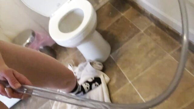 Amateur girl in socks holds clear tube over toilet in piss play tease