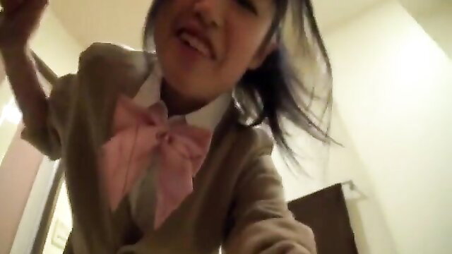 Cute Asian schoolgirl in pink bow tie smiles at POV camera