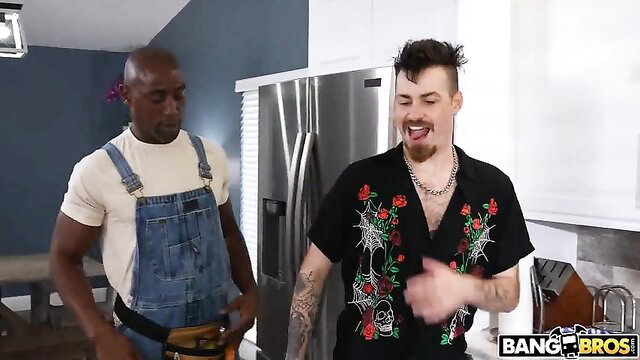 Black overalls handyman and tattooed white guy grinning in kitchen
