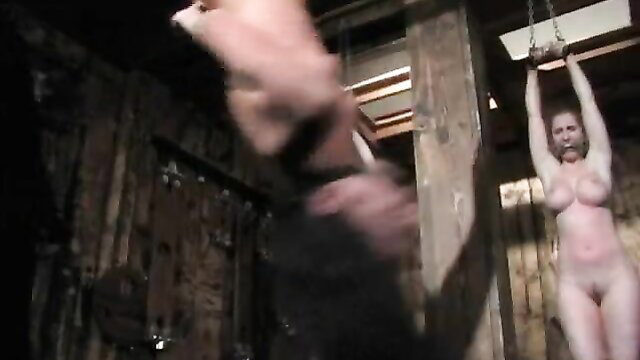 Nude sub hanging upside down gagged, dom man groping in BDSM pain room