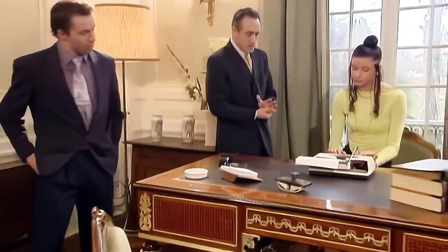 Monica Sweetheart in yellow top at desk with suited men