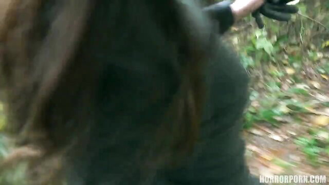 Beautiful bimbo in tight green top and black gloves in forest