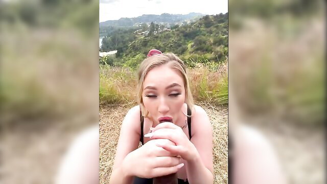 Blonde tart in tank top sips drink outdoors, sultry eyes, amateur vibe