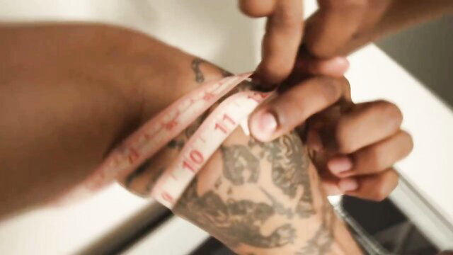 Black muscular man with tattoos measured by woman in hot bodybuilder tease