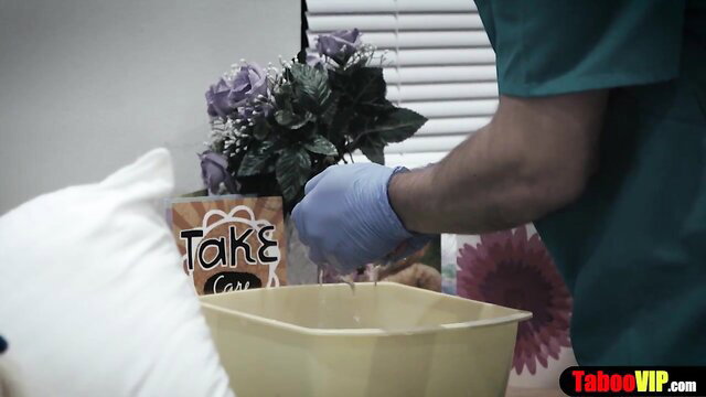 Doctor in scrubs gives gloved patient sponge bath exam