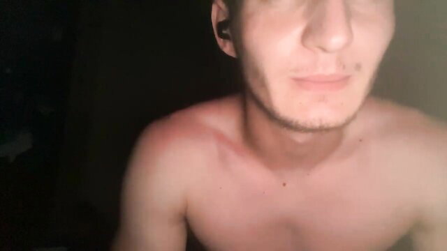 Shirtless young white twink smiles at camera in dim amateur video thumbnail