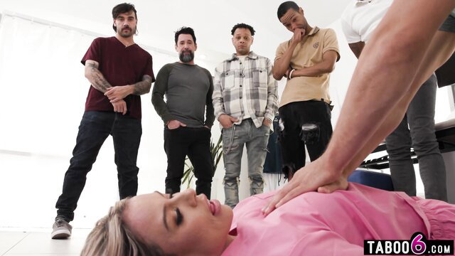 Blonde nurse in pink top surrounded by 5 men in extreme gangbang setup