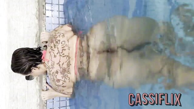 Tattooed Asian woman teases in pool, wet ass up in skimpy pink bikini