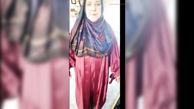 Mature Arab woman in pink hijab dress choosing outfits
