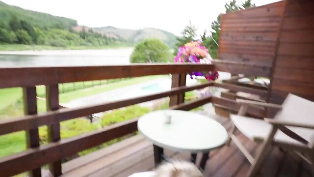 Lena Polanski on scenic balcony with river view and dog